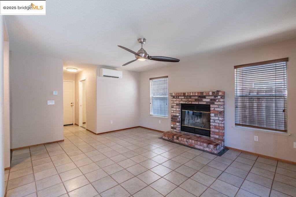 1003 Linda Vista Way Rio Vista, CA 94571 - Photo 24 of 60 Unfurnished living room with a ceiling fan, light tile patterned floors, a fireplace, and a wall mounted AC
