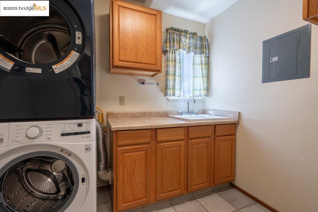1003 Linda Vista Way Rio Vista, CA 94571 - Photo 46 of 60 Washroom with stacked washer / dryer, a textured wall, cabinet space, electric panel, and light tile patterned flooring