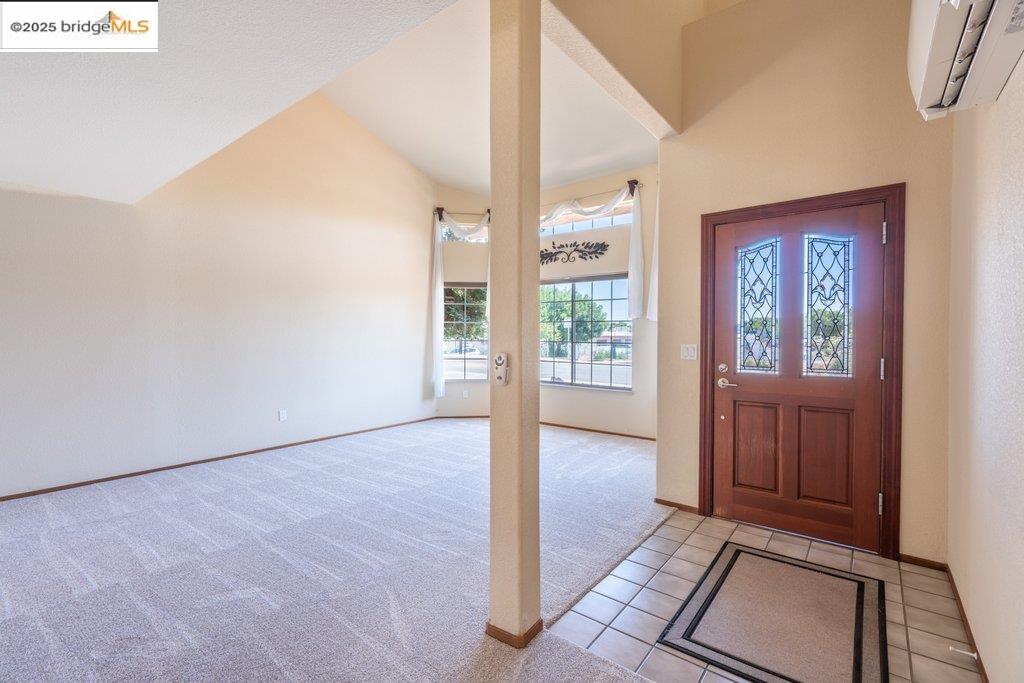 1003 Linda Vista Way Rio Vista, CA 94571 - Photo 7 of 60 Entryway with light tile patterned floors, vaulted ceiling, light colored carpet, and a wall mounted air conditioner