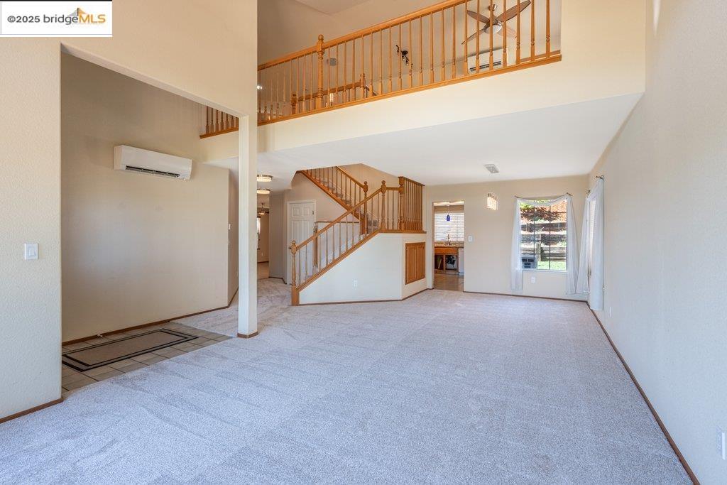 1003 Linda Vista Way Rio Vista, CA 94571 - Photo 10 of 60 Unfurnished living room with a towering ceiling, carpet, an AC wall unit, and stairs
