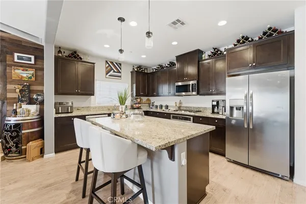 a kitchen with stainless steel appliances kitchen island granite countertop a refrigerator and a sink