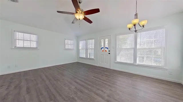 a view of an empty room with a window and wooden floor