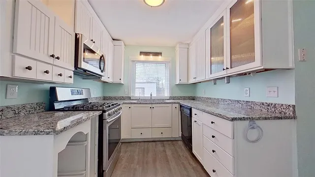 a kitchen with granite countertop a sink a stove and cabinets