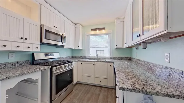 a kitchen with stainless steel appliances granite countertop a stove a sink and a microwave