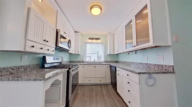 a kitchen with stainless steel appliances granite countertop a stove a sink and a white cabinets
