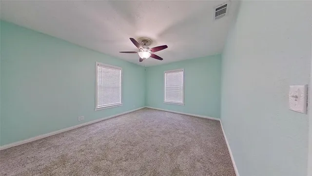 an empty room with a window and a ceiling fan