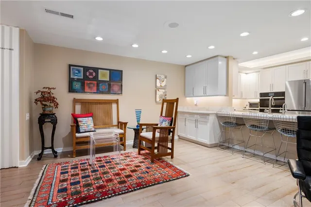 a living room with stainless steel appliances furniture rug and a table