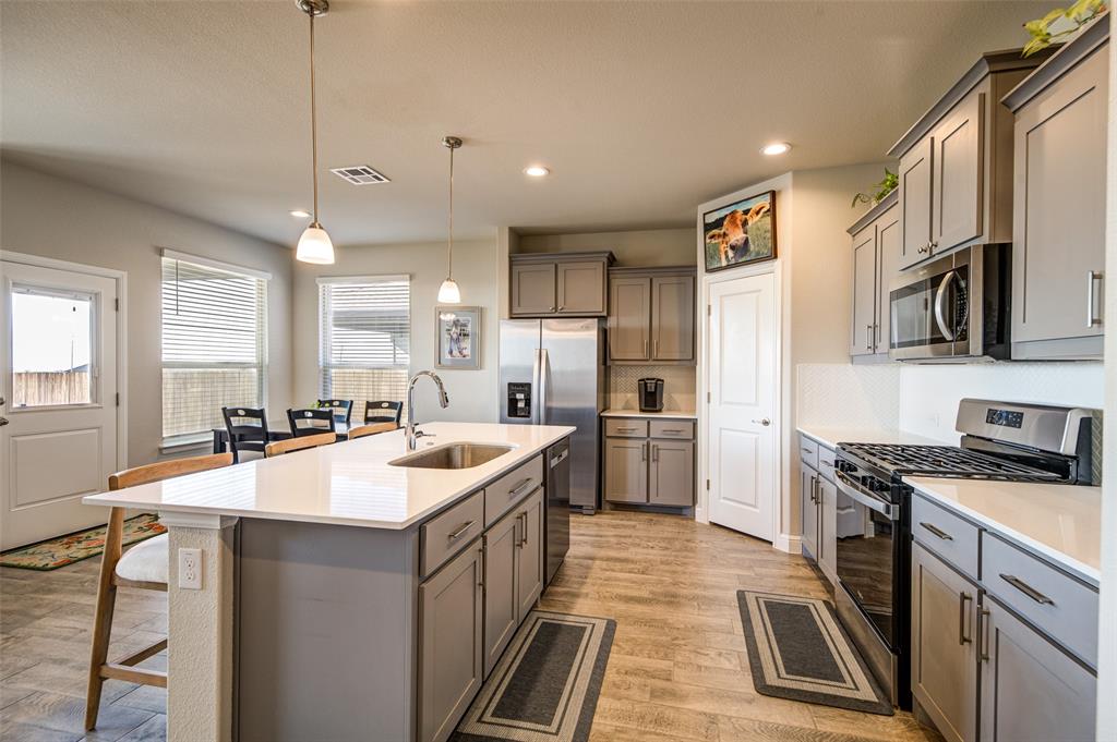 145 Hawksbill Lane Rhome, TX 76078 - Photo 6 of 23 a large kitchen with stainless steel appliances a stove a sink a oven a kitchen island with a cabinets and wooden floor