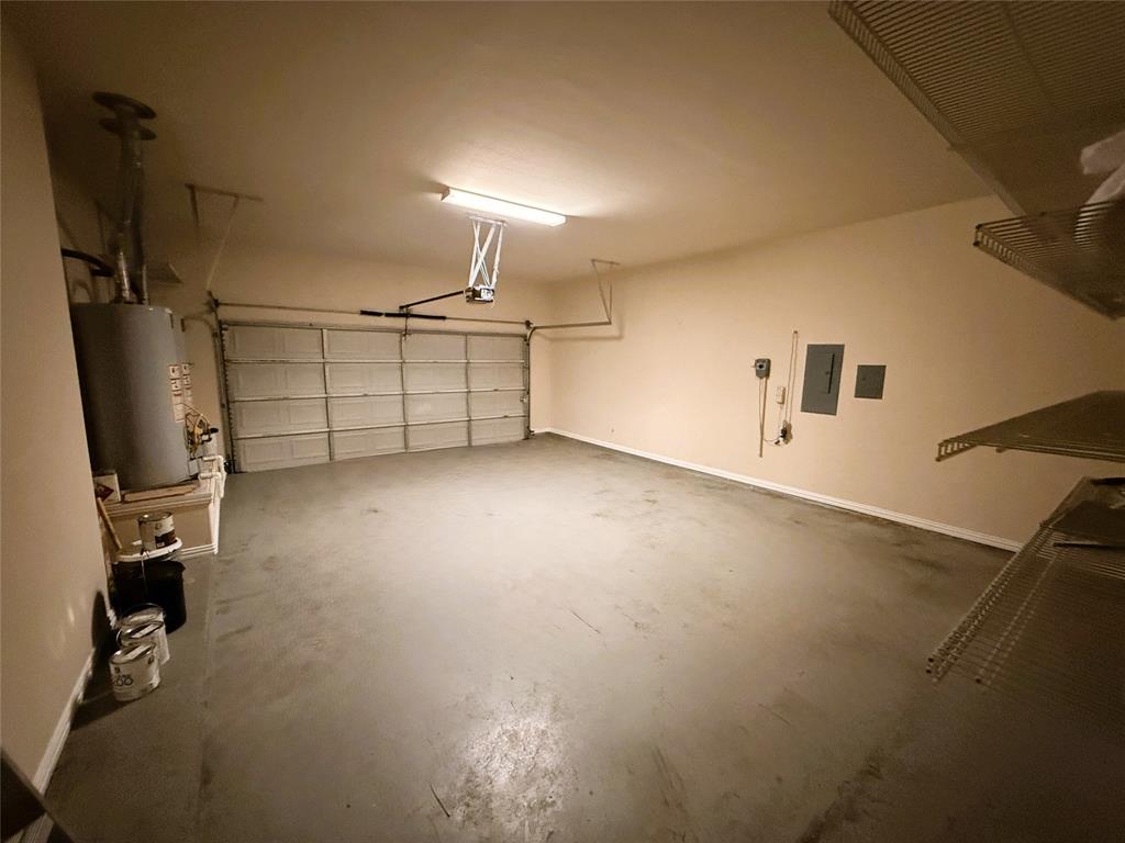 2215 Longview Road Irving, TX 75063 - Photo 25 of 25 Spacious garage featuring a concrete floor, overhead fluorescent lighting, and a roll-up garage door with opener