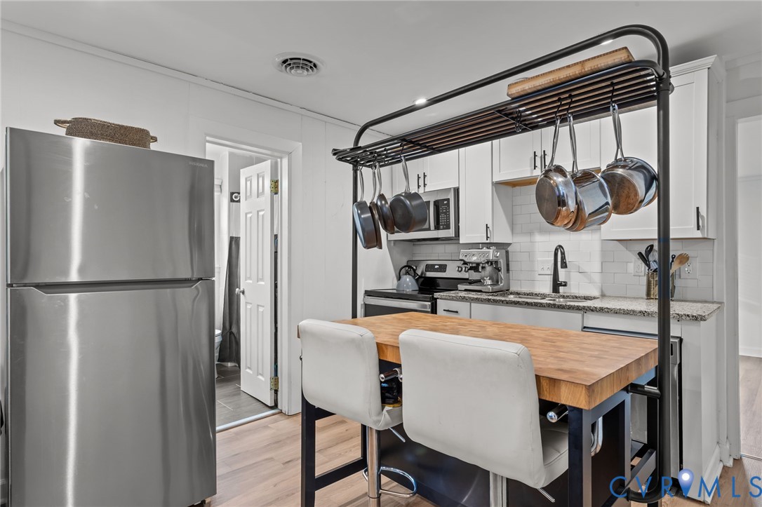 8874 Strath Road Henrico, VA 23231 - Photo 11 of 40 a kitchen with stainless steel appliances granite countertop a refrigerator a sink a stove and island