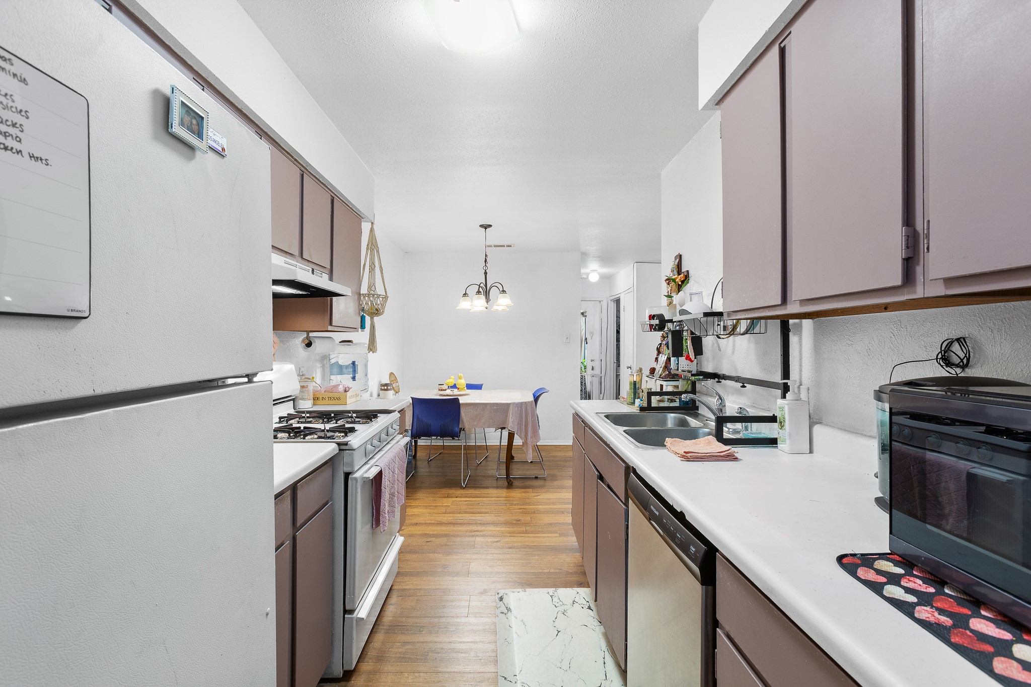 606 Misty Morning Way, Unit A AND B Round Rock, TX 78664 - Photo 11 of 22 Kitchen featuring white appliances, light countertops, light wood-style flooring, and suspended lighting