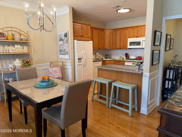 a kitchen with stainless steel appliances granite countertop a stove a refrigerator a dining table and chairs with wooden floor