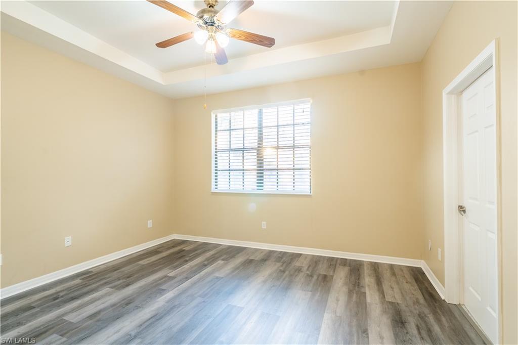 14751 Pinnacle Place, Unit 343 Naples, FL 34119 - Photo 12 of 24 Empty room featuring a raised ceiling, wood finished floors, and a ceiling fan