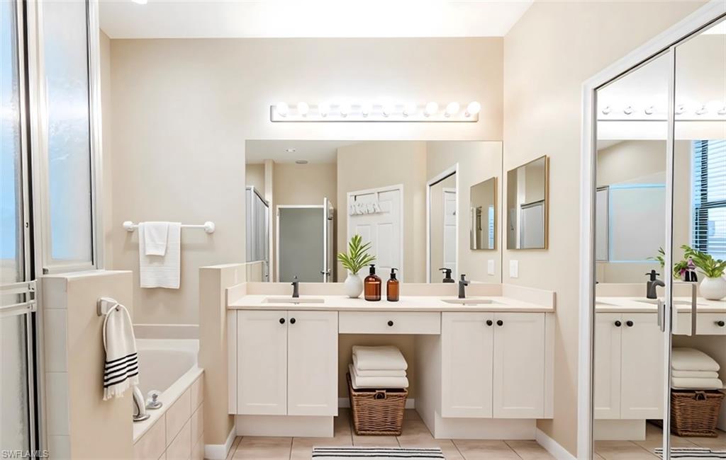 14751 Pinnacle Place, Unit 343 Naples, FL 34119 - Photo 19 of 24 Bathroom with double vanity, a garden tub, a stall shower, and light tile patterned floors