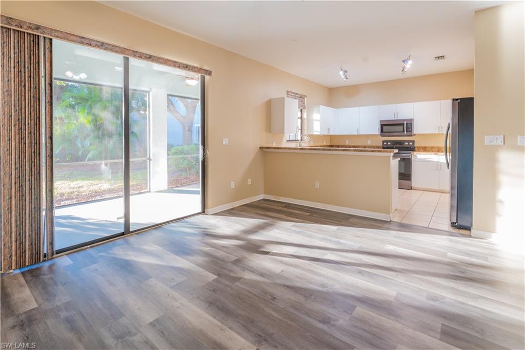 14751 Pinnacle Place, Unit 343 Naples, FL 34119 - Photo 3 of 24 Kitchen with stainless steel appliances, white cabinets, light wood finished floors, and a peninsula