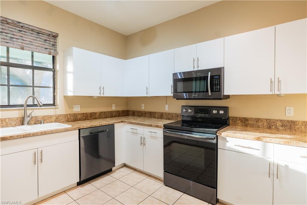 14751 Pinnacle Place, Unit 343 Naples, FL 34119 - Photo 7 of 24 Kitchen featuring black appliances, white cabinets, and light tile patterned floors