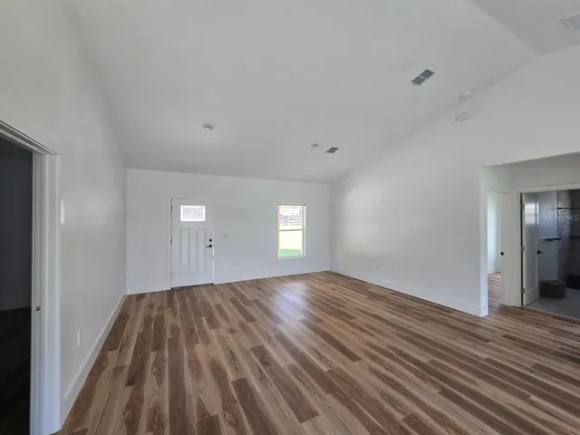 a view of empty room with wooden floor and window