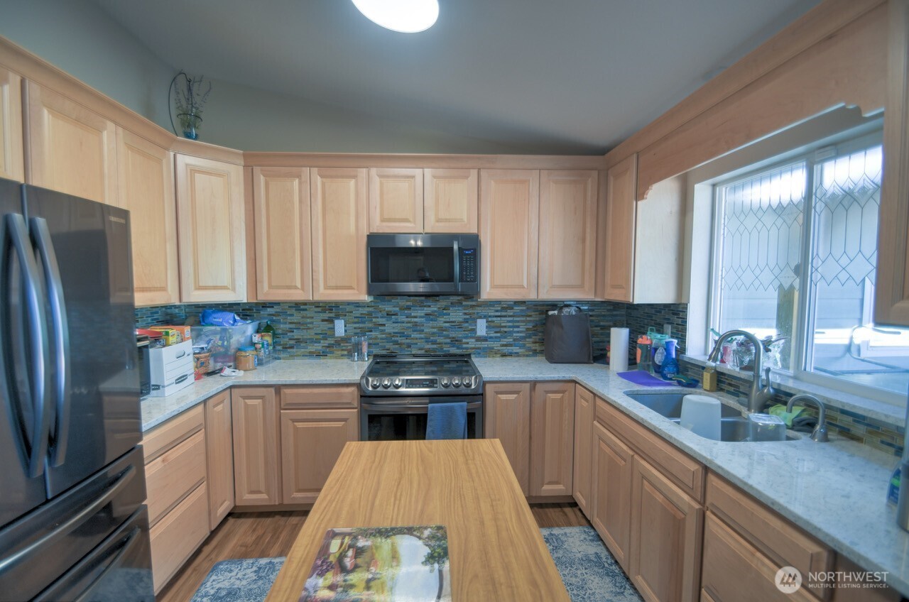 5922 184th Lane Southwest Rochester, WA 98579 - Photo 3 of 34 a kitchen with a sink a refrigerator a microwave and cabinets