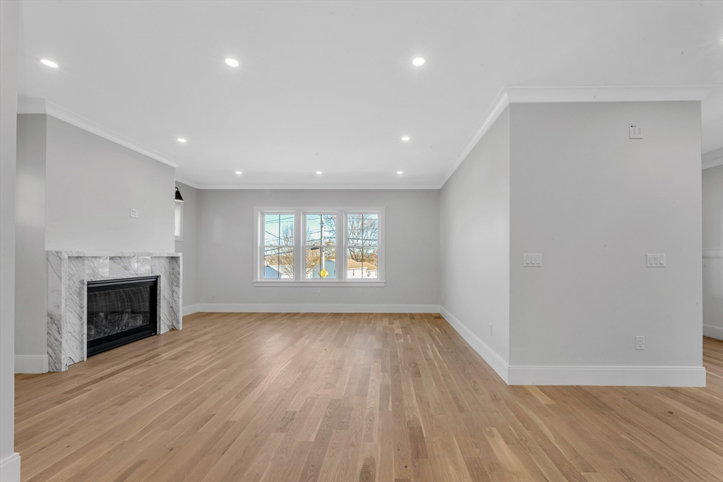 415 Poplar Street Boston, MA 02131 - Photo 4 of 31 an empty room with wooden floor a fireplace and windows
