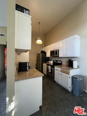 a kitchen with kitchen island granite countertop a sink a stove top oven a counter top space and cabinets