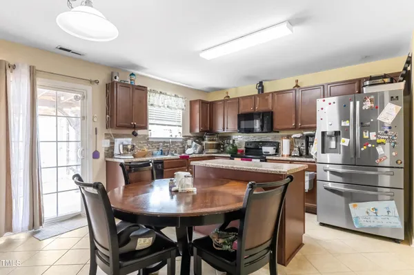 a kitchen with stainless steel appliances granite countertop a stove a refrigerator a sink a dining table and chairs
