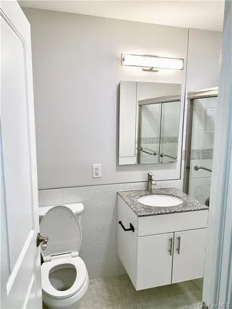 a bathroom with a granite countertop sink vanity mirror and toilet