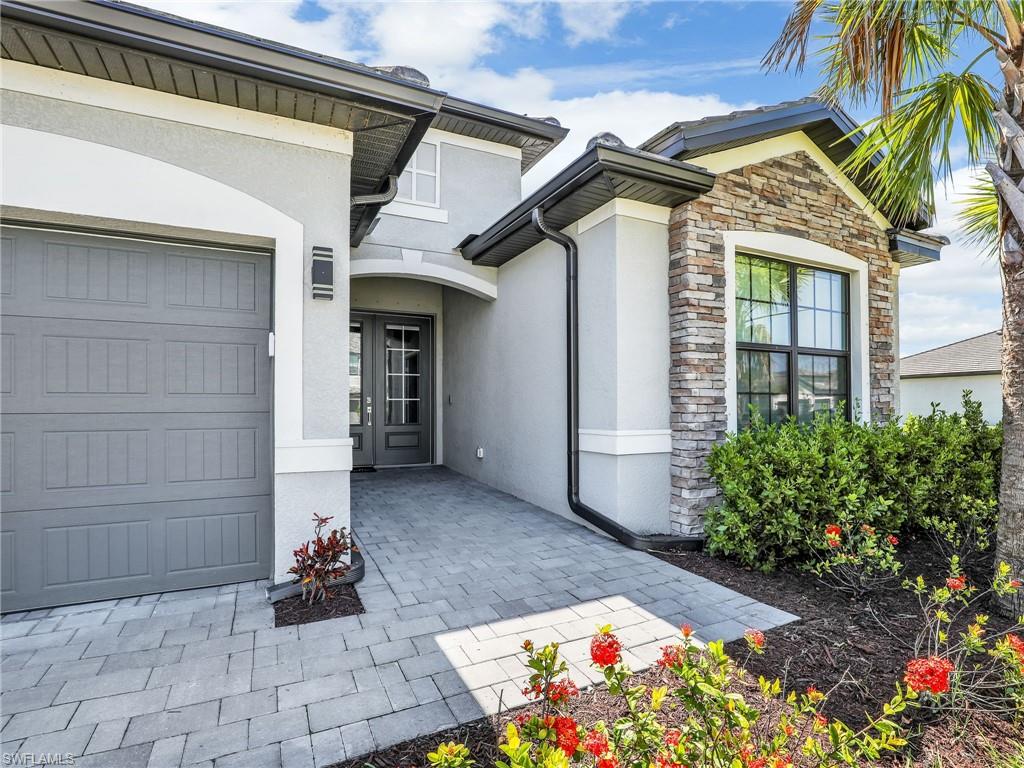 11391 Canopy Loop Fort Myers, FL 33913 - Photo 1 of 43 View of exterior entry featuring stucco siding, stone siding, and an attached garage