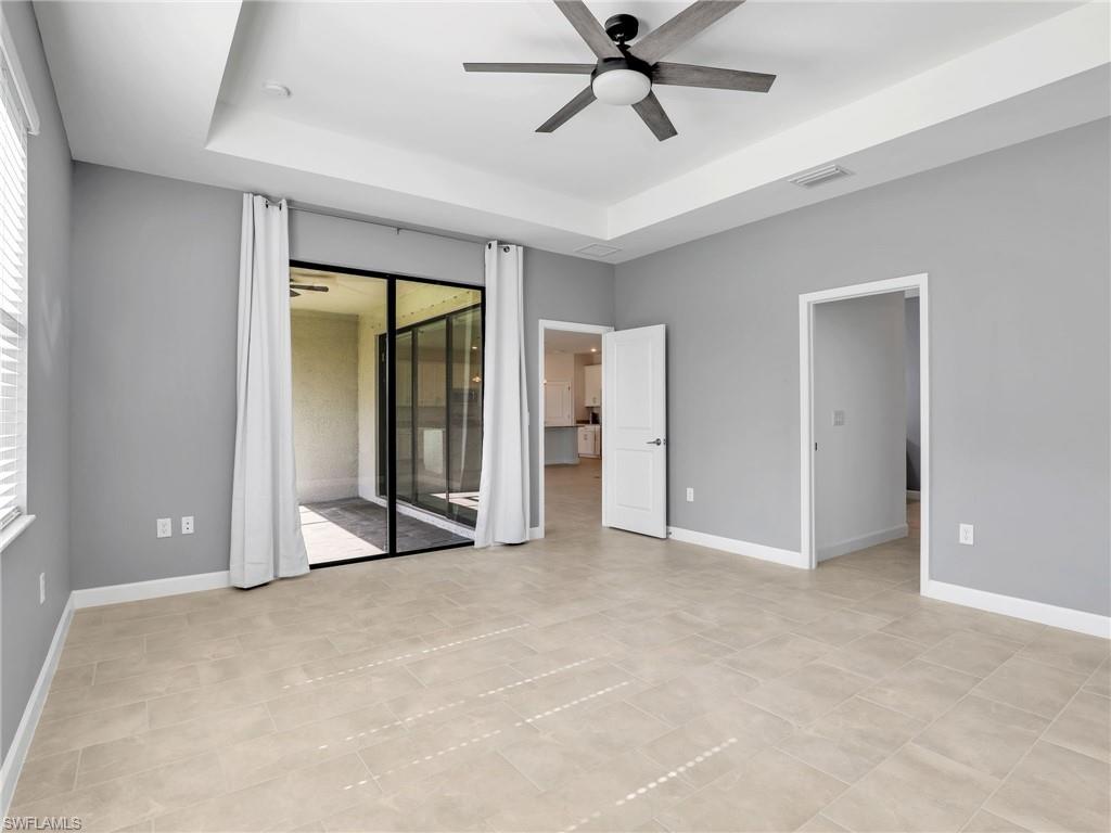 11391 Canopy Loop Fort Myers, FL 33913 - Photo 15 of 43 Unfurnished bedroom featuring a raised ceiling, access to exterior, baseboards, and a ceiling fan