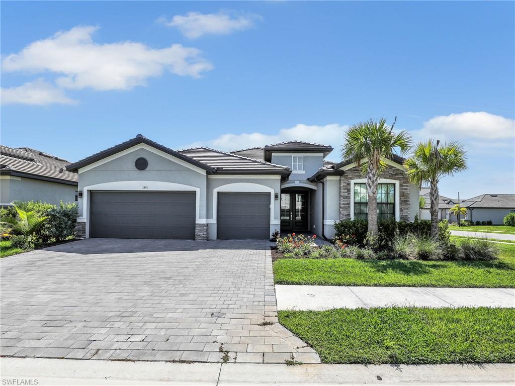 11391 Canopy Loop Fort Myers, FL 33913 - Photo 2 of 43 View of front facade with stone siding, stucco siding, decorative driveway, a garage, and french doors
