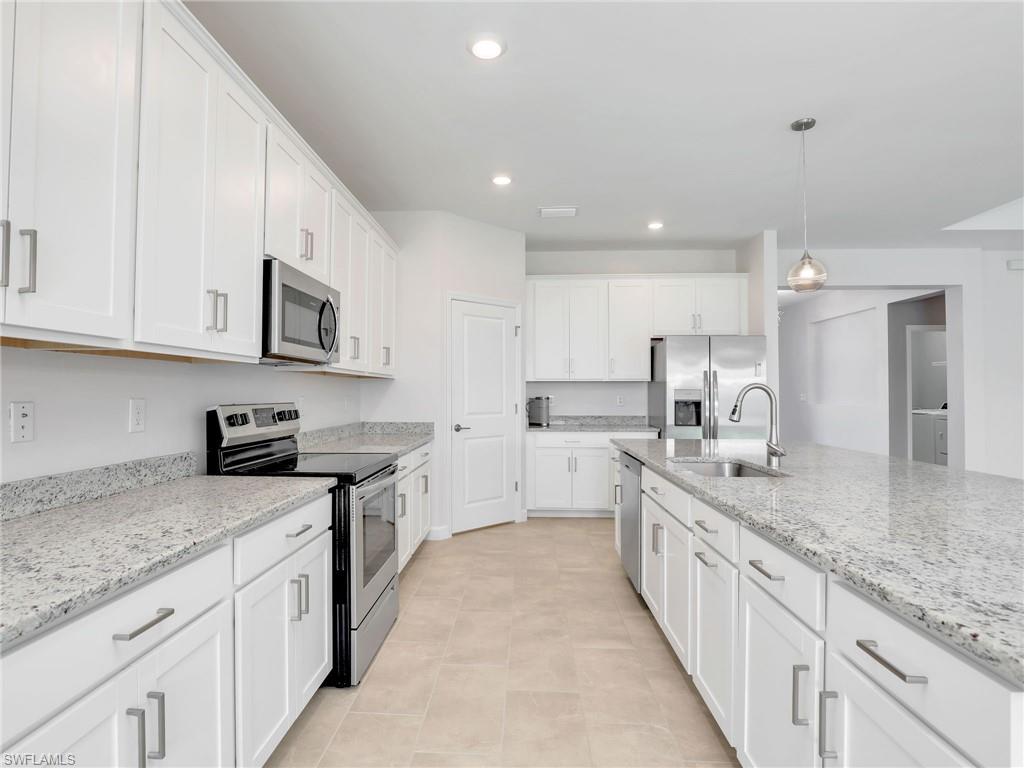 11391 Canopy Loop Fort Myers, FL 33913 - Photo 9 of 43 Kitchen with stainless steel appliances, a sink, white cabinets, hanging light fixtures, and light stone countertops