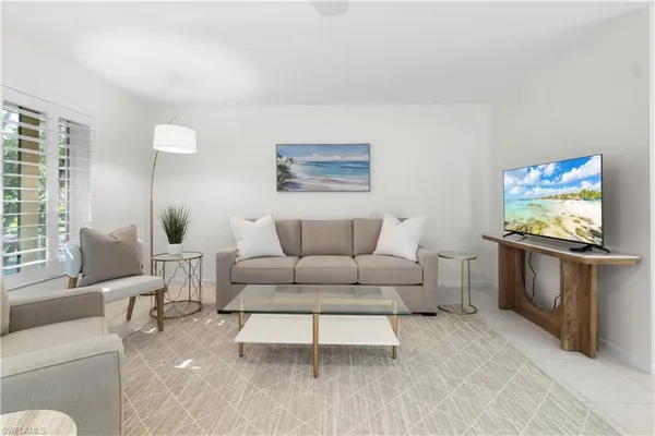 a living room with furniture a flat screen tv and a window