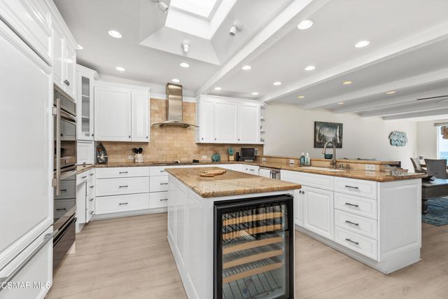 a kitchen with granite countertop a sink stove oven and white cabinets with wooden floor