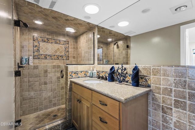 a bathroom with a granite countertop sink a large mirror and shower