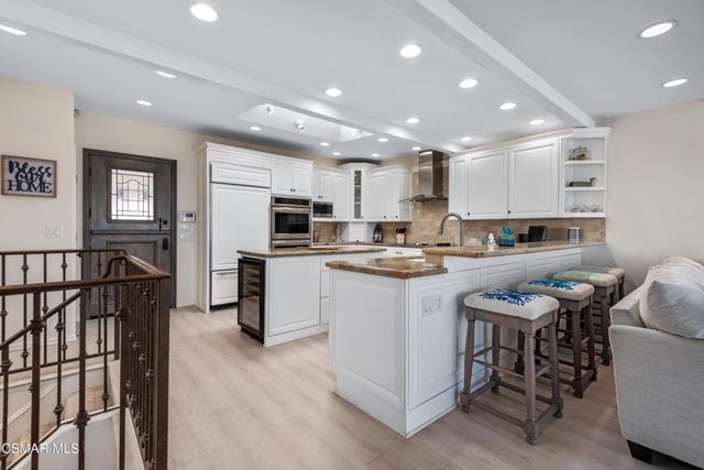 a kitchen with stainless steel appliances kitchen island granite countertop a stove top oven a sink a refrigerator and white cabinets