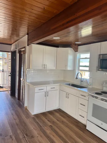a kitchen with granite countertop white cabinets and white appliances