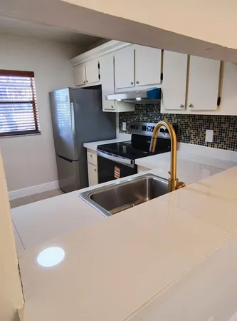 a kitchen with stainless steel appliances granite countertop a sink a stove a refrigerator a microwave a sink and cabinets