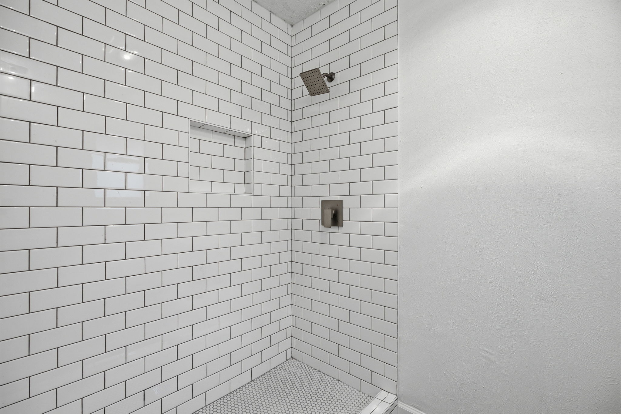 7205 Beckett Road Austin, TX 78749 - Photo 26 of 40 A well-appointed shower space, featuring subway tile walls and a mosaic tile floor, promises a refreshing bathing experience.