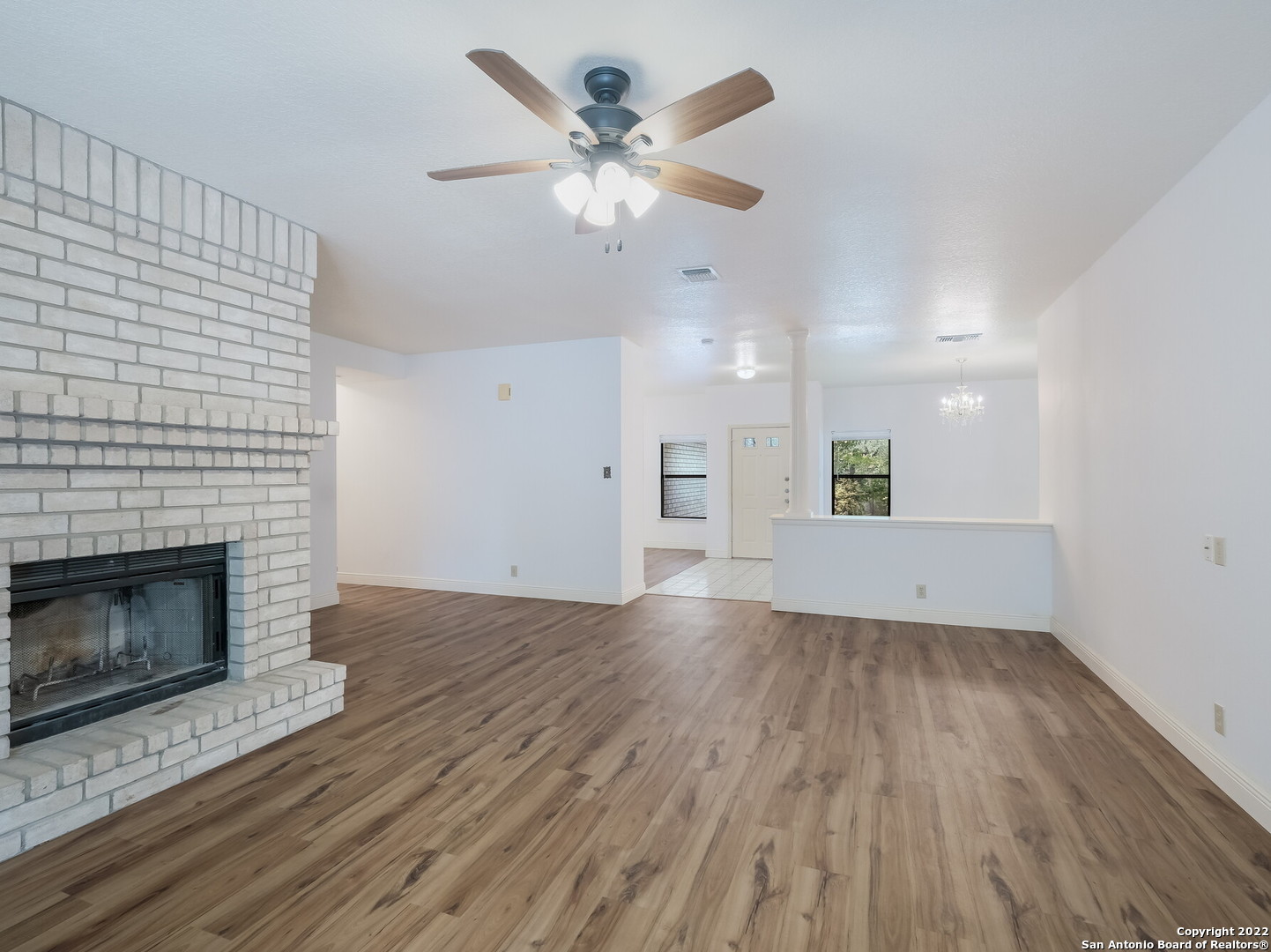 9231 Linbrooke San Antonio, TX 78250 - Photo 9 of 28 an empty room with wooden floor a fireplace a ceiling fan and wooden floor