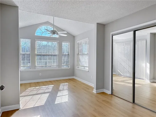 an empty room with wooden floor mirror and windows