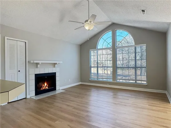 a view of an empty room with wooden floor fireplace and a window