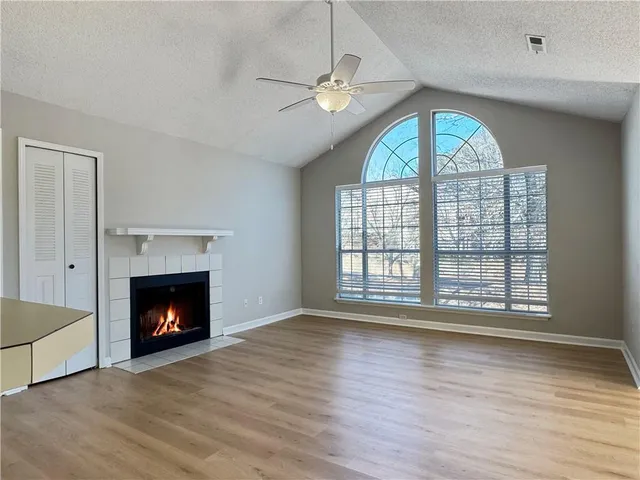 a view of an empty room with wooden floor fireplace and a window