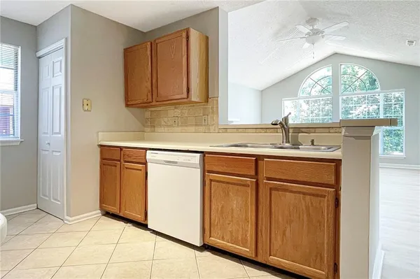 a kitchen with granite countertop a sink stainless steel appliances white cabinets and a window