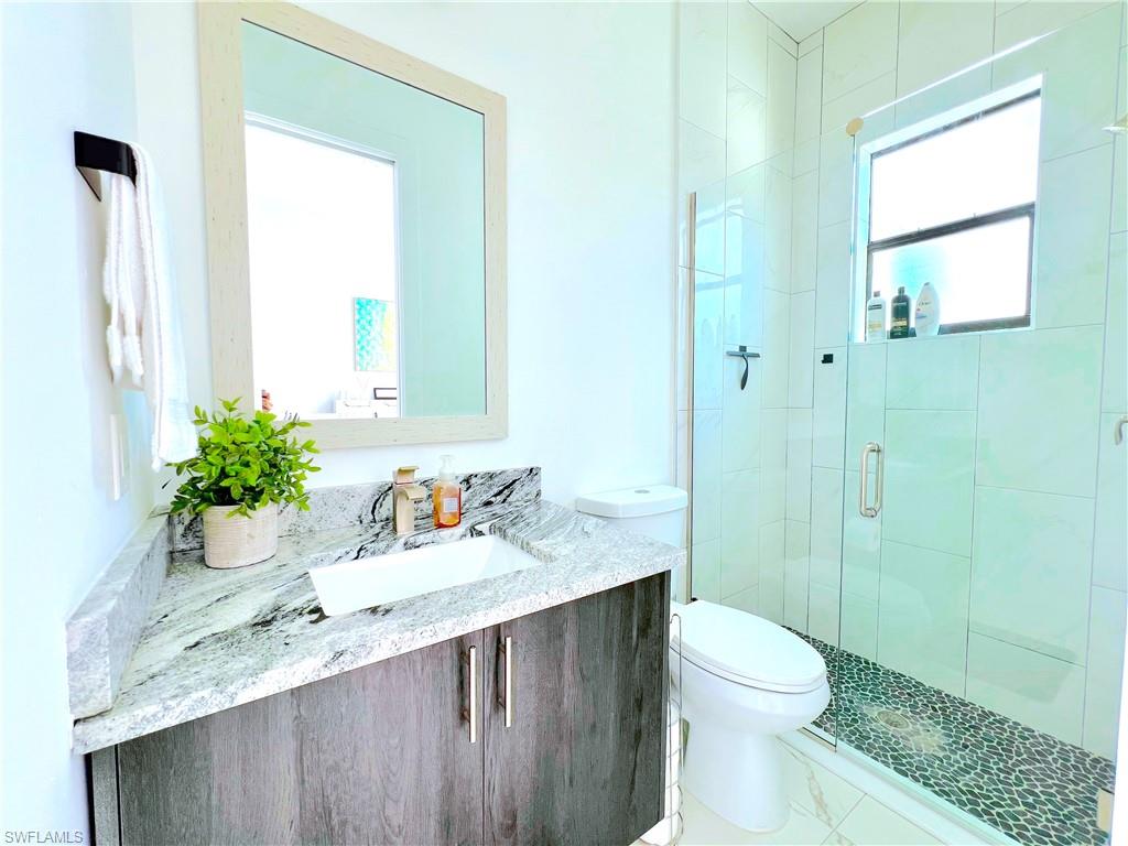 4064 Full Moon Court Naples, FL 34112 - Photo 35 of 50 a bathroom with a granite countertop sink a toilet and shower