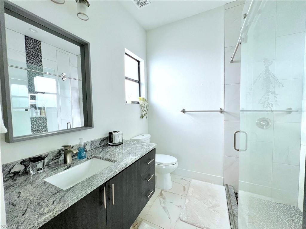 4064 Full Moon Court Naples, FL 34112 - Photo 38 of 50 a bathroom with a granite countertop sink toilet and shower