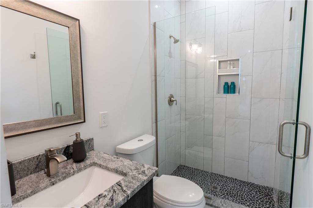 4064 Full Moon Court Naples, FL 34112 - Photo 45 of 50 a bathroom with a granite countertop toilet a sink a shower and a mirror