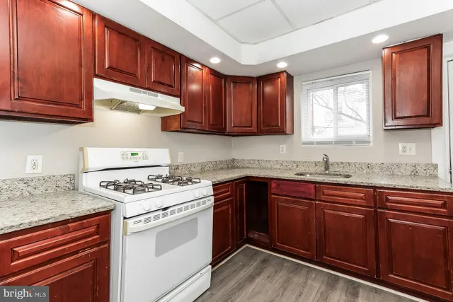 a kitchen with stainless steel appliances granite countertop wooden cabinets stove top oven and sink