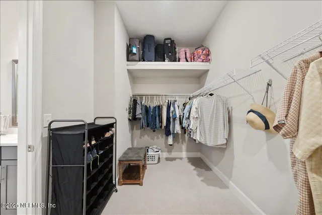 a view of walk in closet with clothes and shoes