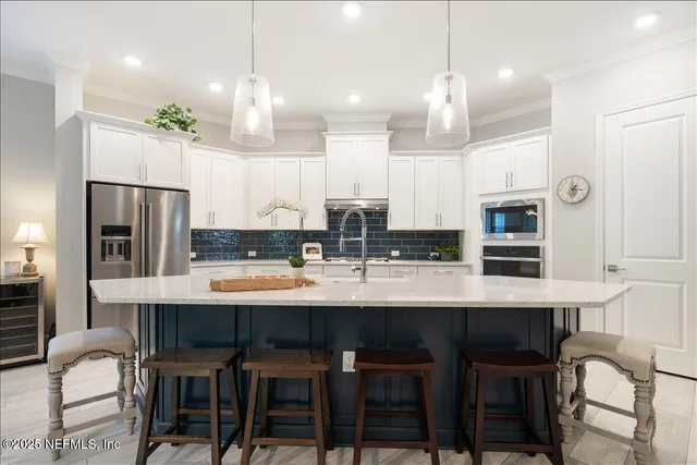 a kitchen with stainless steel appliances a dining table chairs refrigerator and microwave