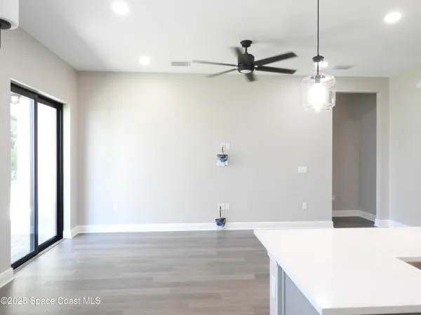 an empty room with wooden floor a ceiling fan and windows