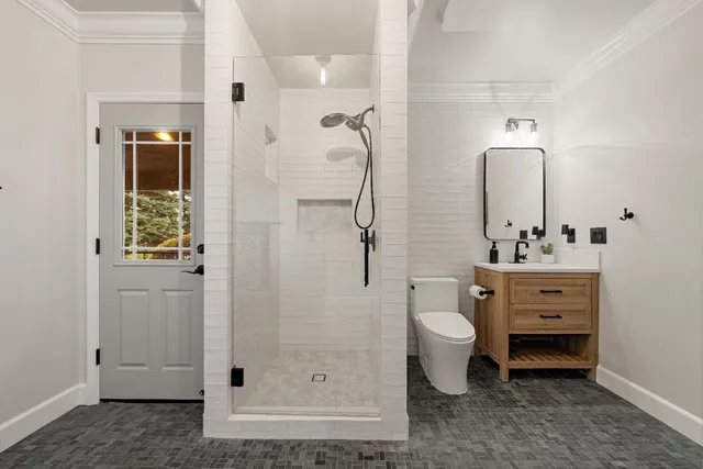 a bathroom with a granite countertop shower sink vanity mirror and toilet